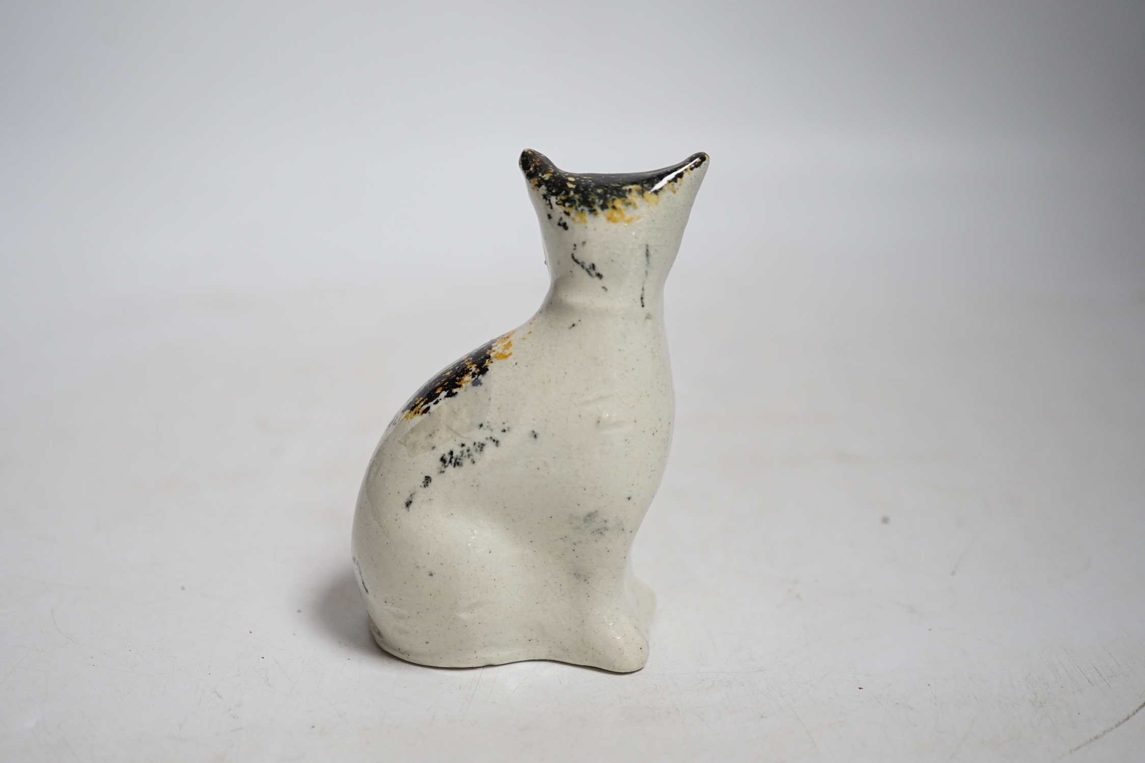 A Staffordshire pottery cat with yellow collar, mid 19th century, height 9.5cm